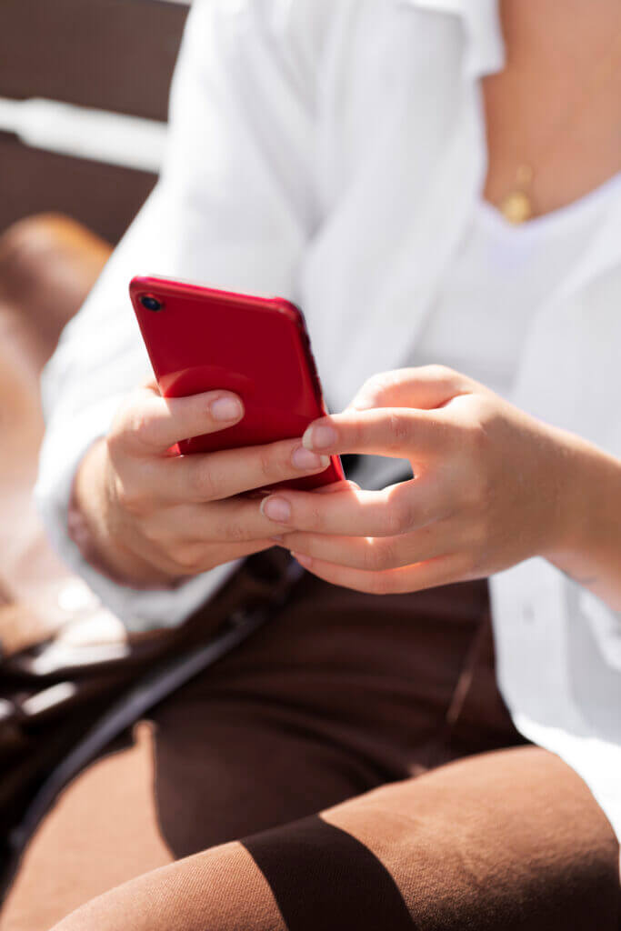 pecado-mortal (3) Mãos segurando um celular vermelho (alerta), simbolizando a tentação e o perigo do Pecado Mortal na vida moderna.